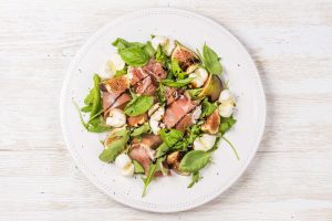 Fresh salad with prosciutto, rocket, fig and basil, drizzled with Moro Frutal Extra Virgin Olive Oil
