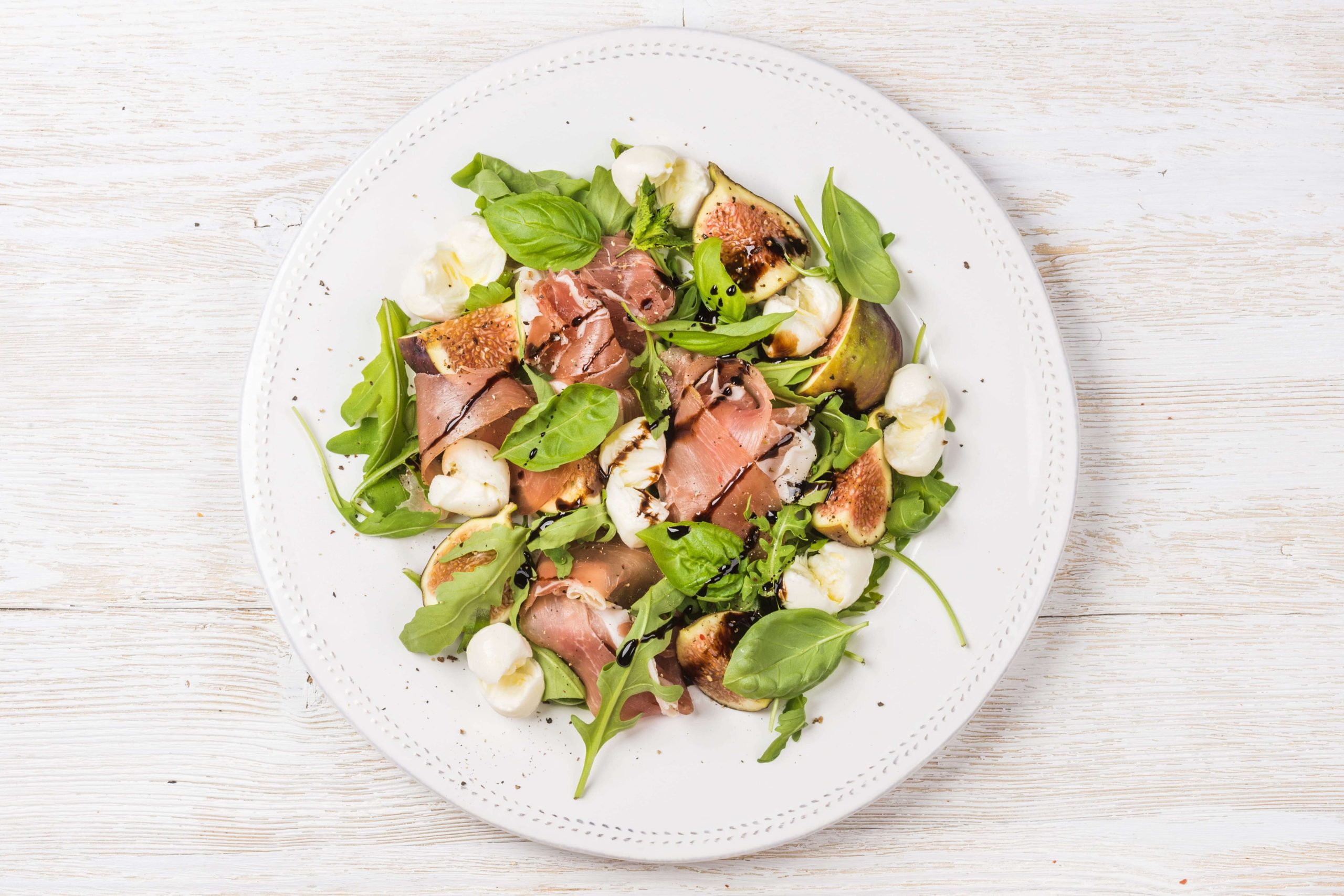 Fresh salad with prosciutto, rocket, fig and basil, drizzled with Moro Frutal Extra Virgin Olive Oil